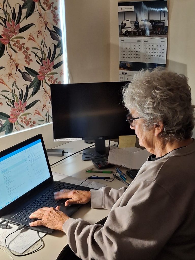 Brigitte at her computer writing an urgent email to the urologist explaining Jean's hearing impairment