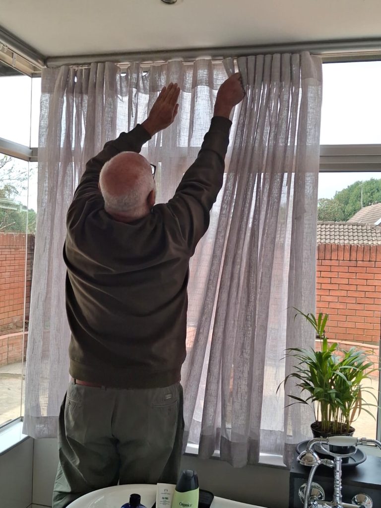 Jean installing curtains in a home